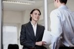 Smartly-dressed woman talking to person in an office asking the best questions on an open day