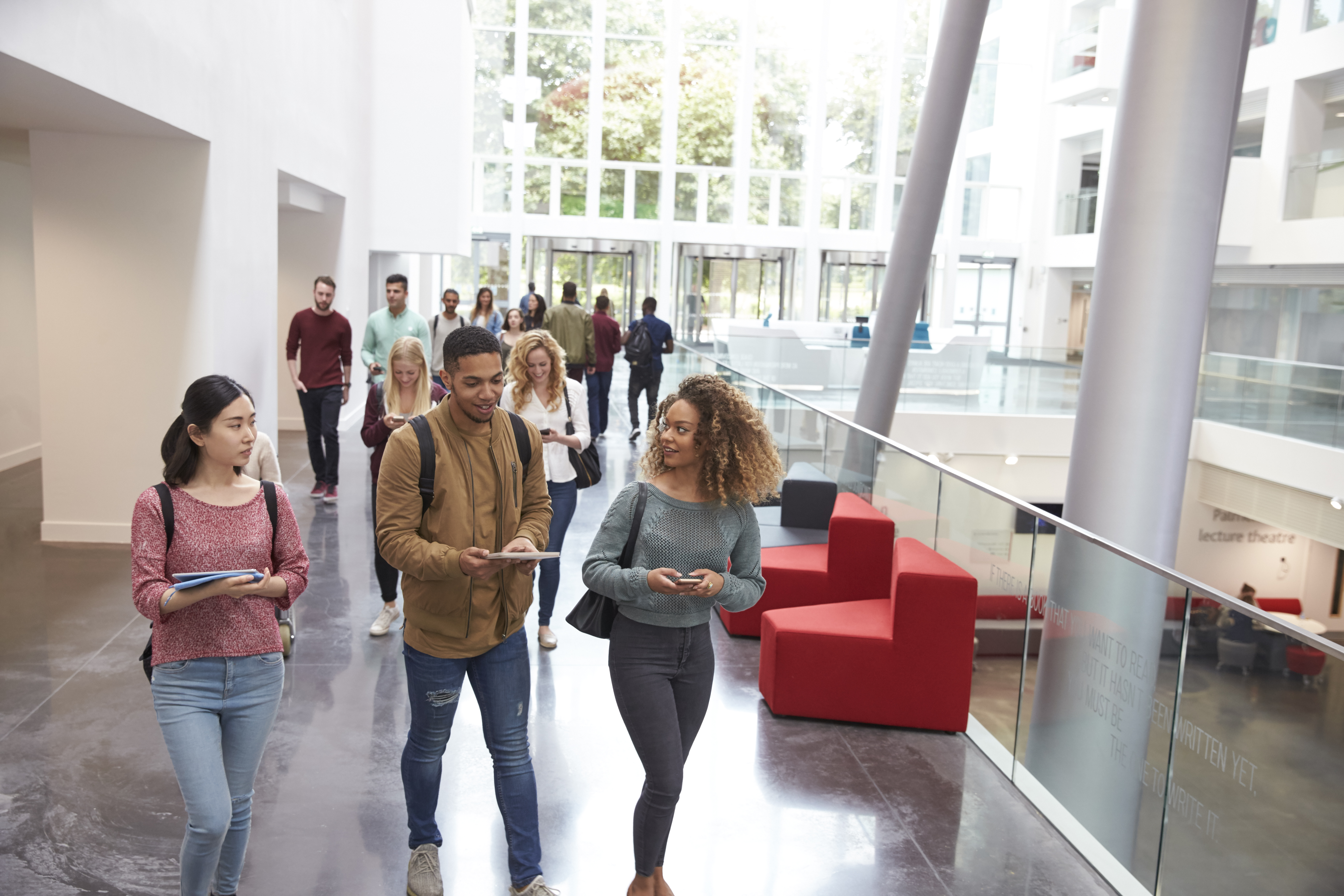 A group of students walk through a large modern university building