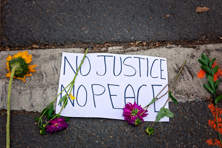 Banner reading "no justice, no peace" surrounded by flowers