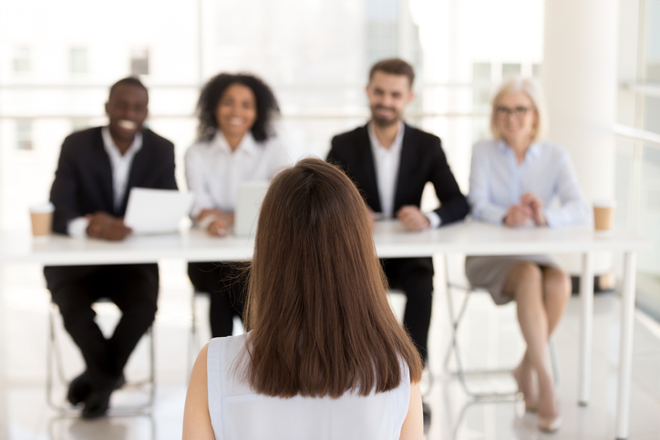 Panel of professionals facing a brown-haired lady at an interview