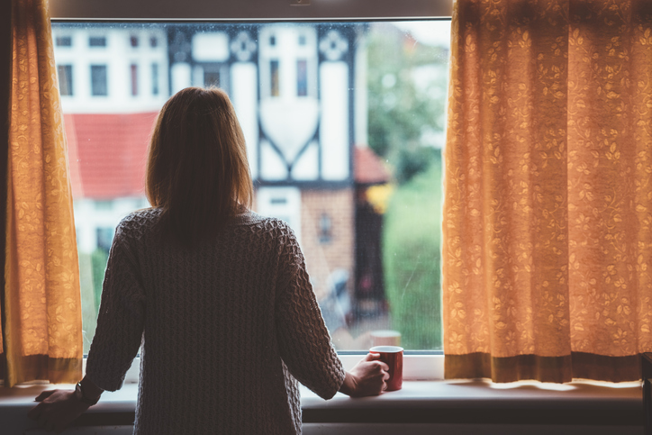 Young woman self isolating looking out of the window