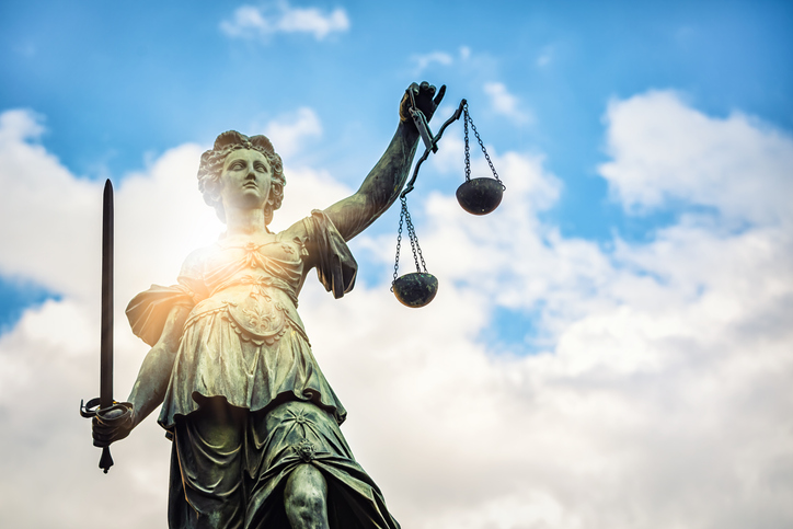 Lady justice statue from below with clouds in the background