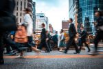 Blurred image of people walking accross a street in a metropolitan area