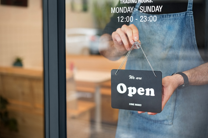 Shop worker placing an "open" sign in the shop window