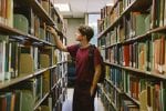 A student in the library looking at and picking out books