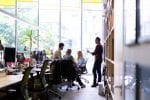 People sit and stand together in a light and airy office space