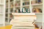 A pile of books with a pair of glasses on top