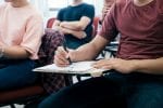 Students sit in a classroom writing on paper