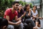 A group of uni students sit together talking and laughing