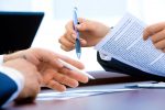 Paperwork closeup with two people signing documents